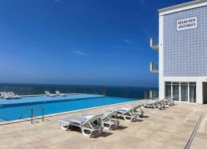 a row of lounge chairs next to a swimming pool at Ocean View Apartments in Lourinhã