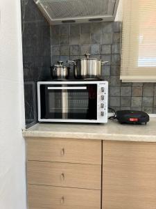 a microwave oven with two pots on top of it at SO SIMPLE mouresi in Mouresi