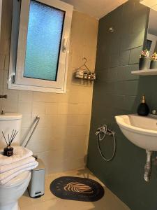 a bathroom with a sink and a toilet and a window at SO SIMPLE mouresi in Mouresi