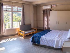 a bedroom with a bed and a chair and a window at Teecee in Āīzawl