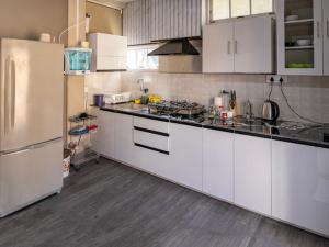 a kitchen with white cabinets and a white refrigerator at Teecee in Āīzawl +12 photos