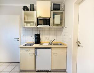 a kitchen with a sink and a microwave at Apartment Pangani Teichhof Fehmarn in Wenkendorf +34 photos