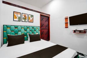 a bedroom with a bed with a green headboard and a tv at Hotel O Shiv Shakti Inn in Sangrāmgarh