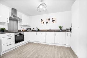 a white kitchen with white cabinets and a wooden floor at Stylish Apartment - Twin Beds - Parking - Fast Wi-Fi 9CC in Birmingham