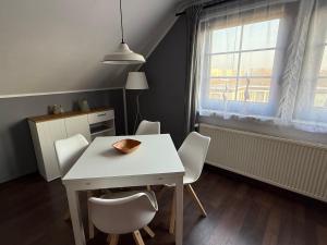 a dining room table with white chairs and a window at Strandgut- unsere Kleine in Dranske