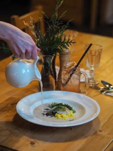 a person pouring sauce onto a plate of food at Starý Svět in Wotitz