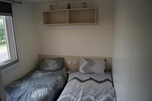 two beds in a small room with a window at Mobile home 8 personnes in Sérignan