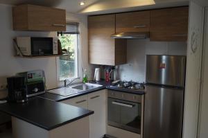 a kitchen with a stainless steel refrigerator and a sink at Mobile home 8 personnes in Sérignan