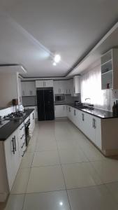 a large kitchen with white cabinets and black appliances at The Rock BnB in Francistown
