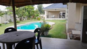 a table and chairs in a yard with a pool at The Rock BnB in Francistown