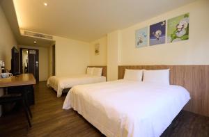a hotel room with two beds and a desk at Traveller Inn - Rail Haus in Taitung City