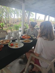two women sitting at a table with plates of food at Solar House Hotel in Dickwella
