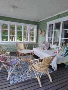 a porch with chairs and a couch and a table at Pensar Hotelli & Ravintola Sandvik in Nauvo +150 photos