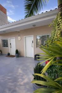 a house with two white doors and some plants at Studio Romã térreo com cozinha in Curitiba