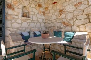 a table and chairs in front of a stone wall at Villa Lida Aresti by Sealand Villas in Agios Leon