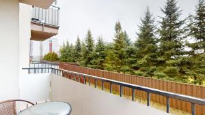 a balcony with a chair and some trees at Apartament Fibra Latte in Rybnik