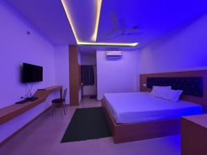a bedroom with a bed and a tv and purple lights at Hotel Glitter in Guwahati +4 photos