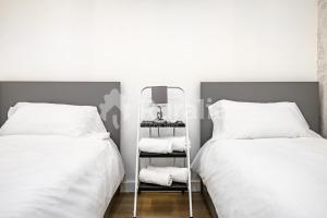 a bedroom with two beds with white sheets and a mirror at QUINTA PORTIELLO Ribadesella in Ribadesella