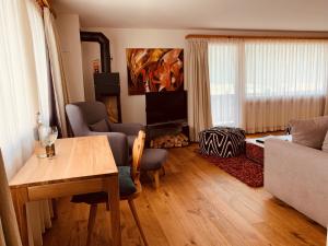 a living room with a table and a tv at Ferienwohnungen Albana in Silvaplana