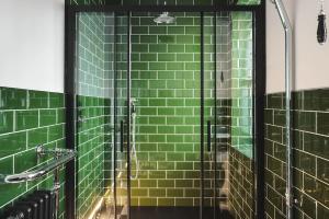 a green tiled shower with a glass door at Old Earth - Ridgestone in Kendal