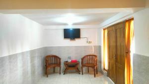 a room with two chairs and a table with a tv at Hotel Nur Cahaya - Syariah in Probolinggo