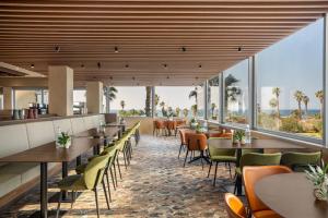 a restaurant with tables and chairs and large windows at Dan Panorama Tel Aviv Hotel in Tel Aviv