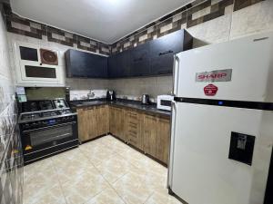 a kitchen with a white refrigerator and wooden cabinets at Giza - faisal in Cairo +3 photos