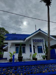 a white house with a blue roof and a palm tree at Blue Beach Villa Anyer in Pasauran