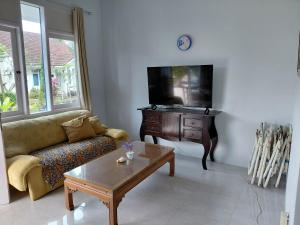 a living room with a couch and a tv and a table at Blue Beach Villa Anyer in Pasauran