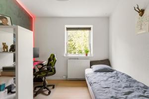 a bedroom with a bed and a desk and a window at Mårslet - close to ocean and city in Mårslet