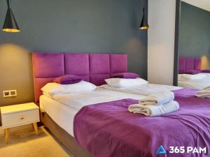 a bedroom with two beds with purple headboards at 365PAM - Apartament nr 32 w Mielenku - BASEN KRYTY, ANIMACJE DLA DZIECI, JACUZZI, SAUNA,PLAC ZABAW W CENIE in Mielenko