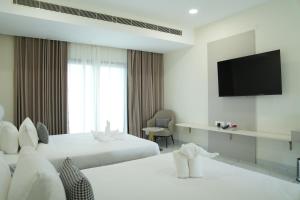 a hotel room with two beds and a flat screen tv at Firefox Hotel and Resort in Moinabad