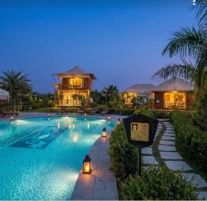 a large swimming pool with a house in the background at Luxe Stayz Signature Pushkar in Pushkar