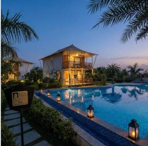 a large swimming pool with a house in the background at Luxe Stayz Signature Pushkar in Pushkar