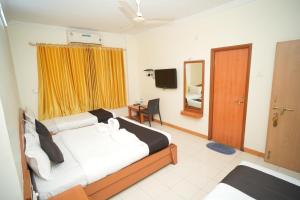 a bedroom with two beds and a desk and a mirror at HOTEL ABHISHEK, Shirdi in Shirdi