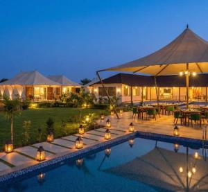 a resort with a swimming pool and a patio with tables at Luxe Stayz Signature Pushkar in Pushkar