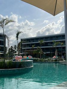 a swimming pool in front of a building at Flats Beach Class Verano - Muro Alto, Porto de Galinhas in Ipojuca