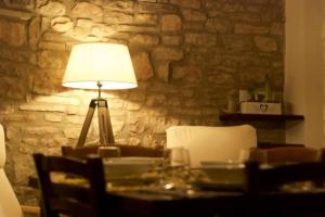 a table with a lamp and a stone wall at Delizioso Appartamento Francesco House Family in Assisi