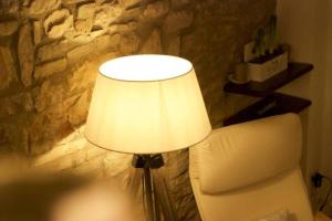 a lamp next to a chair and a stone wall at Delizioso Appartamento Francesco House Family in Assisi