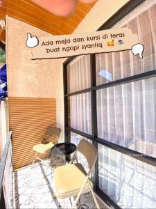 a balcony with chairs and a sign on the wall at Villa Syahdu1 Tawangmangu in Tawangmangu