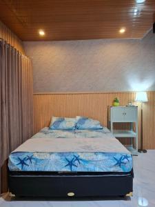 a bedroom with a bed with a blue comforter at Villa Syahdu1 Tawangmangu in Tawangmangu