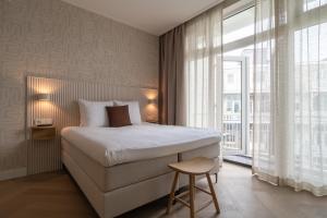a bedroom with a bed and a large window at Hotel Zest Den Haag - Scheveningen in Scheveningen