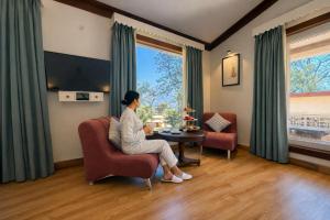 a woman sitting in a chair in a room with a table at Yog Niketan Villa in Rishīkesh