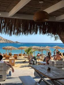 a beach with tables and umbrellas and the ocean at Hotel Delfini in Mylopotas