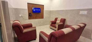 a waiting room with red chairs and a television at 3BHK - Bamboo Private Pool Villa Yercaud in Yercaud
