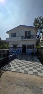 a large white house with a checkered floor at 3BHK - Bamboo Private Pool Villa Yercaud in Yercaud