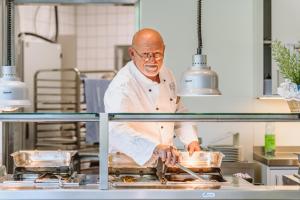 a chef standing in a kitchen preparing food at Hotel Gustav-Stresemann-Institut in Bonn