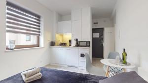 a kitchen with white cabinets and a table and chairs at Studio Fibra Choco in Rybnik +9 photos