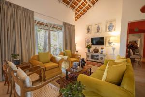 a living room with a yellow couch and chairs at Heuvel Villa Kandy in Kandy