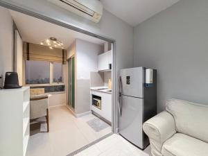 a kitchen with a refrigerator and a table and a couch at MUXA Condo - Centric Sea in Pattaya
